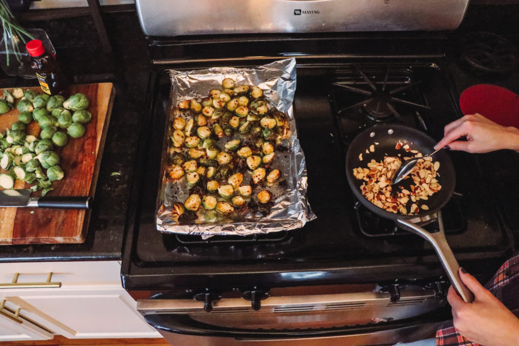 Honey Roasted Brussel Sprouts by popular Nashville life and style blog, Nashville Wifestyles: image of honey roasted Brussel sprouts next to a pan of roasted slivered almonds.