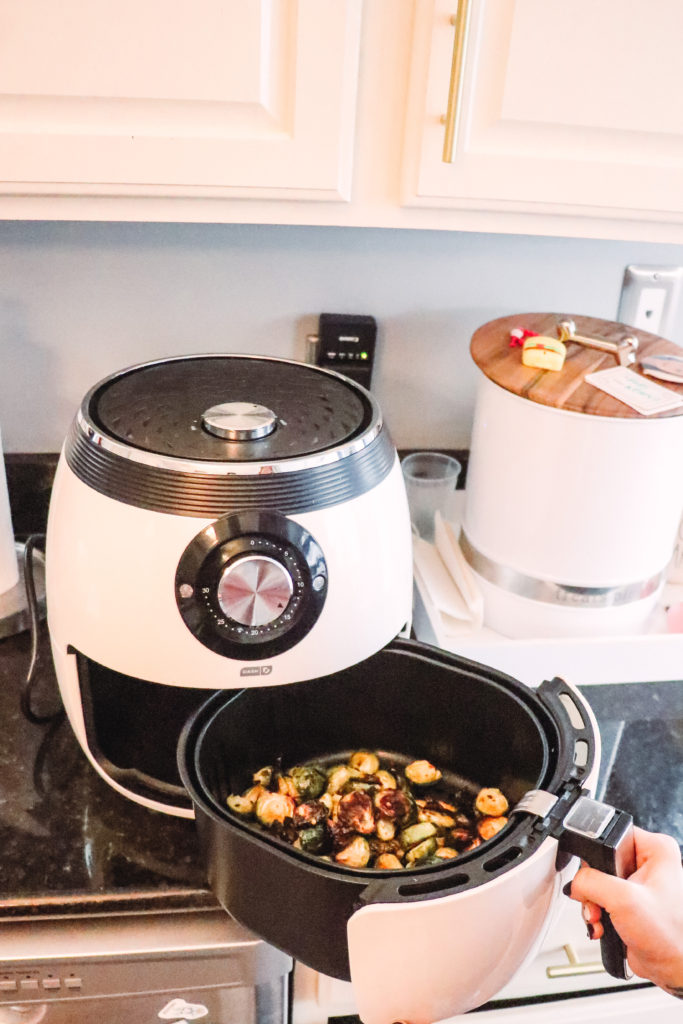 Honey Roasted Brussel Sprouts by popular Nashville life and style blog, Nashville Wifestyles: image of a woman putting honey roasted Brussel sprouts in a air fryer.
