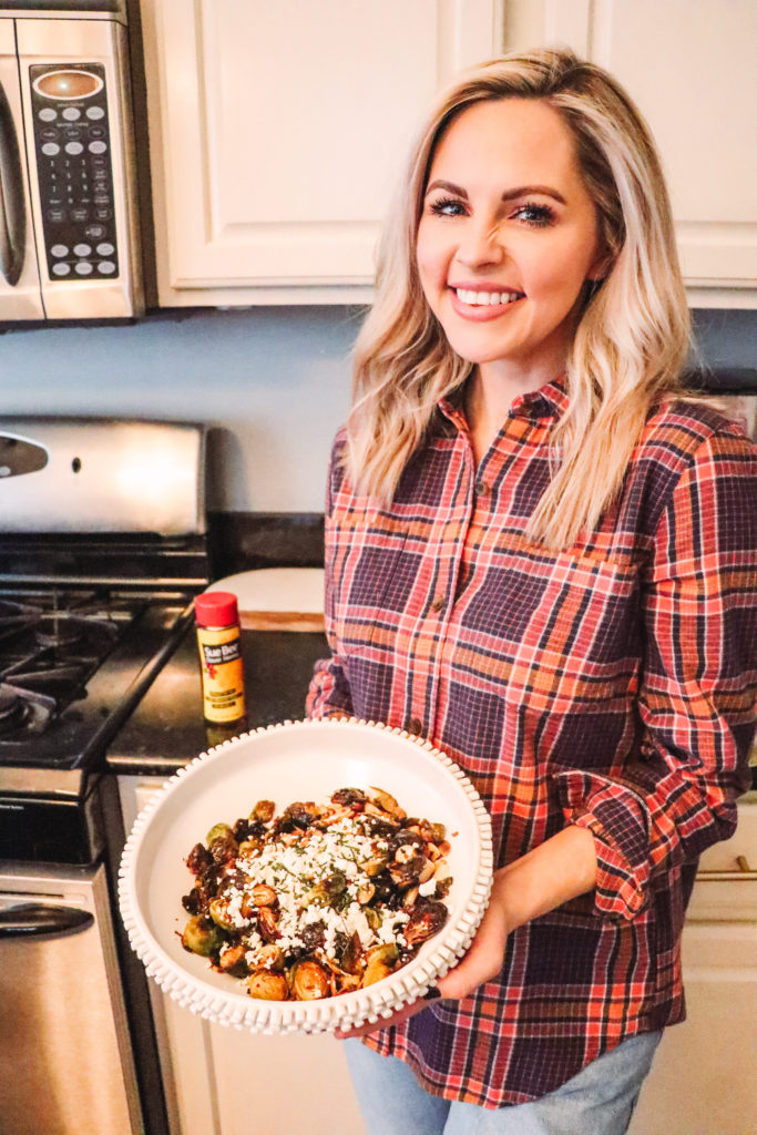 Honey Roasted Brussel Sprouts by popular Nashville life and style blog, Nashville Wifestyles: image of a woman holding a white ceramic bowl containing honey roasted Brussel sprouts.