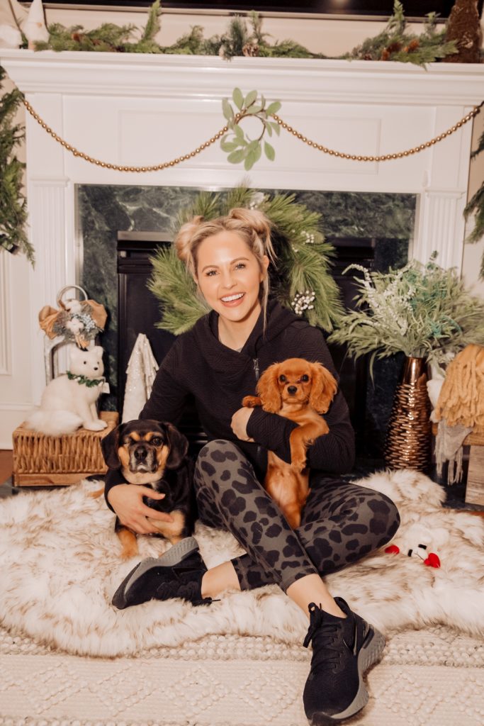 Pet Parent by popular Nashville lifestyle blog, Nashville Wifestyles: image of a woman sitting in front of a fireplace while holding her two dogs. 
