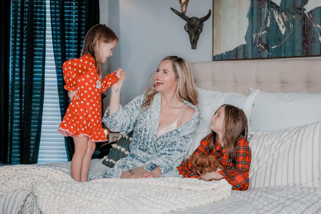 Best Loungewear by popular Nashville fashion blog, Nashville Wifestyles: image of a woman sitting in bed with her two daughters and wearing a plush blue leopard print robe. 