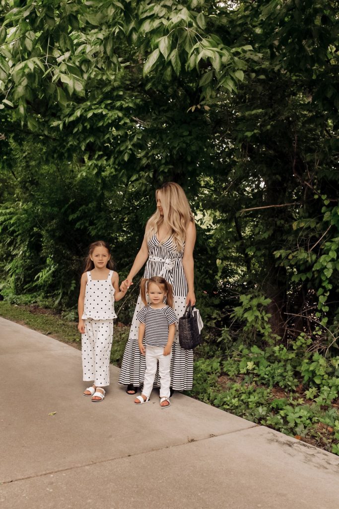Coping Skills for Kids by popular Nashville motherhood blog, Nashville Wifestyles: image of a mom wearing a black and white jumpsuit while standing next to her daughters outside who are wearing a black and white polka dot romper and a black and white stripe top with white pants. 