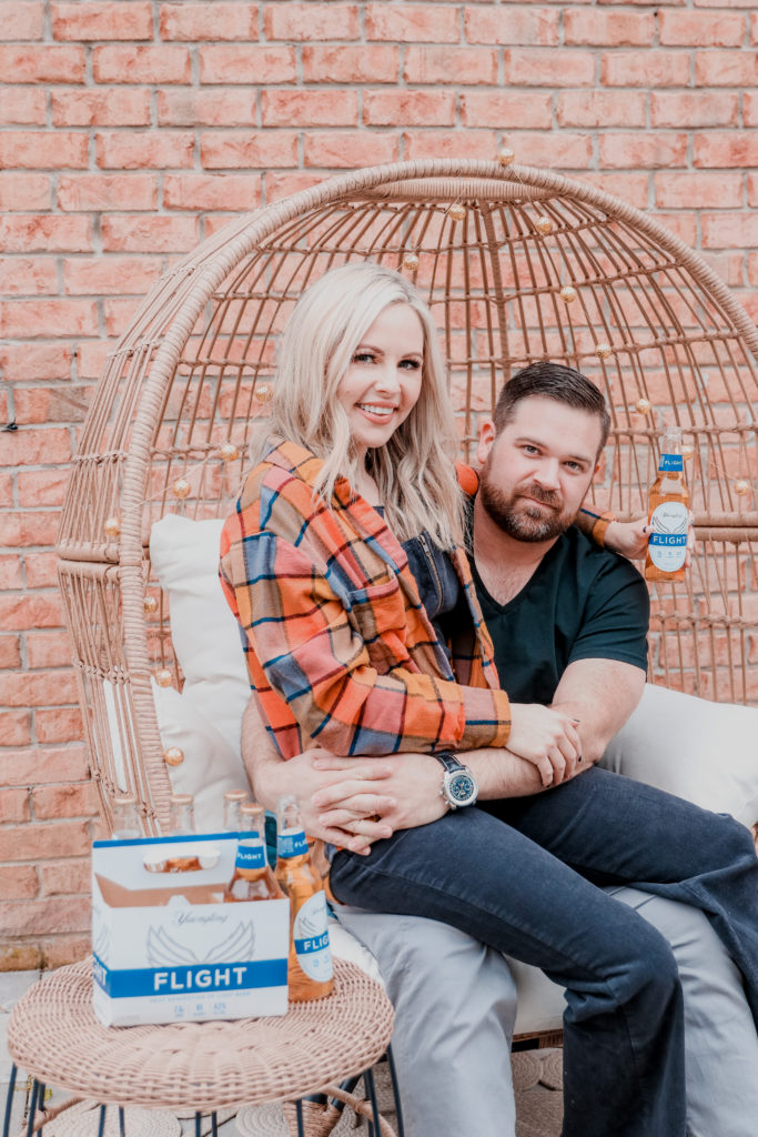 Date Night In Ideas by popular Nashville lifestyle blog, Nashville Wifestyles: image of a woman sitting on a man's lap and holding a bottle of Flight beer. 