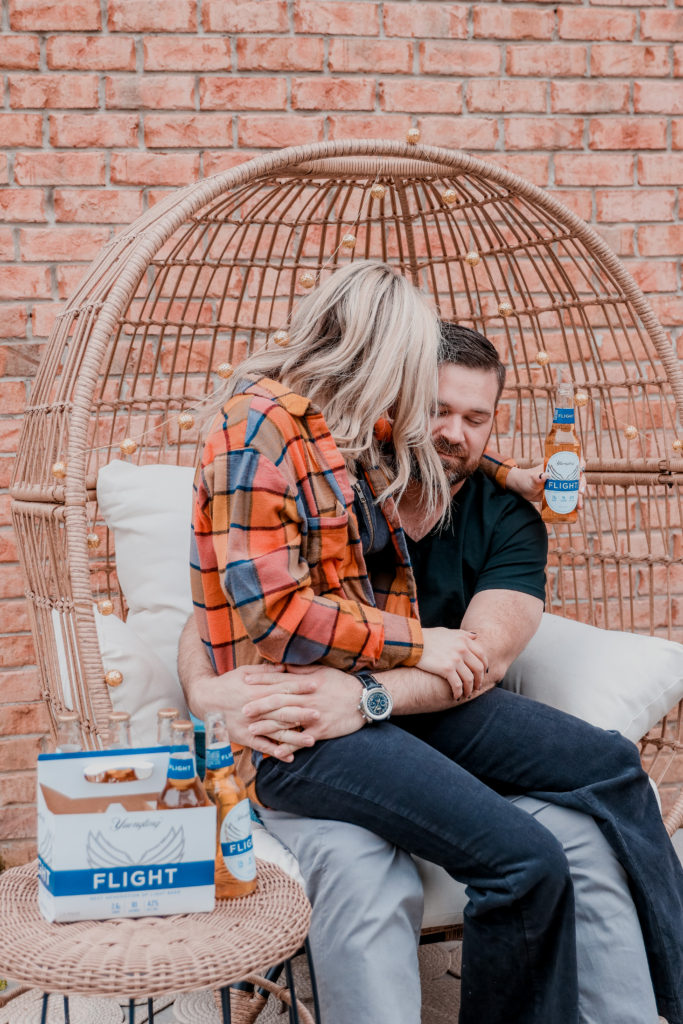 Date Night In Ideas by popular Nashville lifestyle blog, Nashville Wifestyles: image of a woman sitting on a man's lap and holding a bottle of Flight beer. 