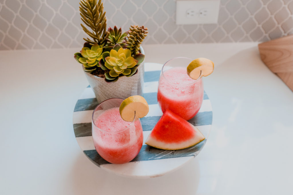 Watermelon Margarita by popular Nashville lifestyle blog, Nashville Wifestyles: image of watermelon margaritas in stemless wine glasses on a cake stand next to a watermelon slice and a succulent plant. 
