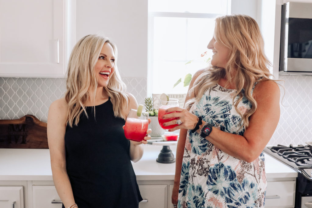 Watermelon Margarita by popular Nashville lifestyle blog, Nashville Wifestyles: image of two women standing next to each other in a kitchen and holding watermelon margaritas in a stemless wine glasses.