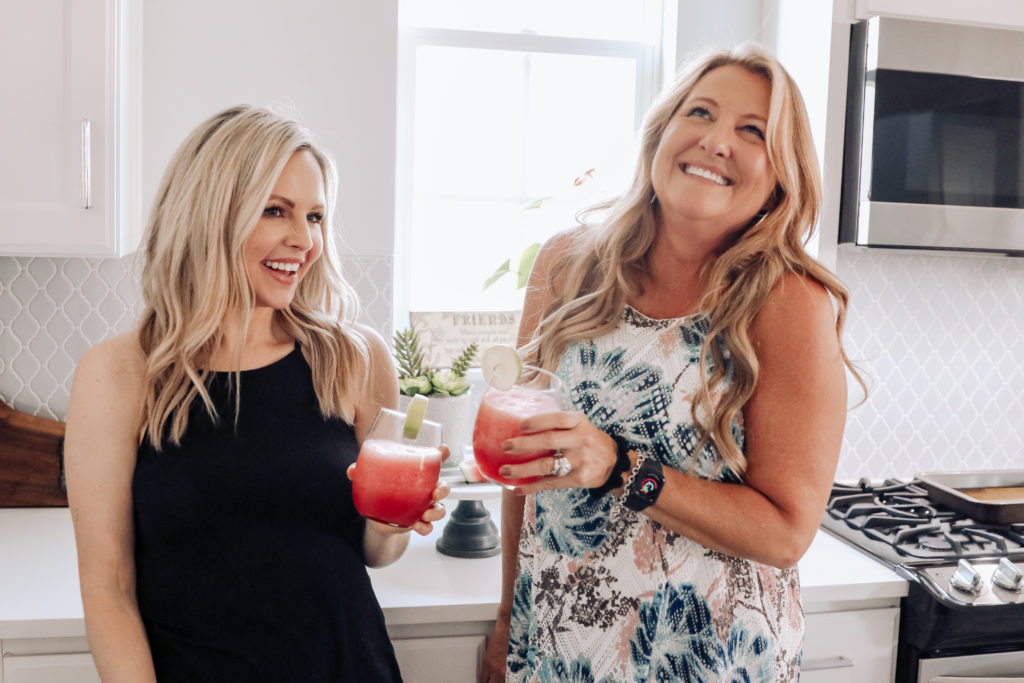 Watermelon Margarita by popular Nashville lifestyle blog, Nashville Wifestyles: image of two women standing next to each other in a kitchen and holding watermelon margaritas in a stemless wine glasses.