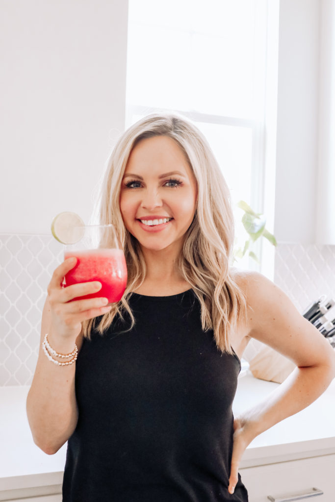 Watermelon Margarita by popular Nashville lifestyle blog, Nashville Wifestyles: image of a woman wearing a black tank and holding a watermelon margarita in a stemless wine glass. 