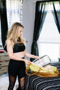 Travel Tips by popular Nashville travel blog, Nashville Wifestyles: image of a woman wearing a black workout outfit and packing her carry-on bag. 