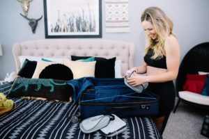Travel Tips by popular Nashville travel blog, Nashville Wifestyles: image of a woman wearing a black workout outfit and packing her suitcase. 