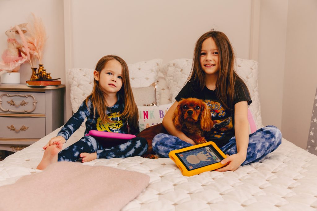Benefits of Owning a Pet by popular Nashville lifestyle blog, Nashville Wifestyles: image of two young girls sitting together on a bed with their dog. 