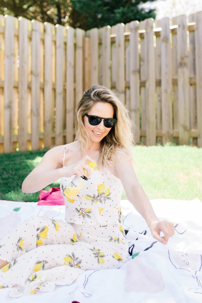 Sun Tanning Tips by popular Nashville beauty blog, Nashville Wifestyles: image of a woman sitting on a blanket in her backyard and applying some sunscreen. 