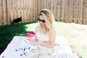 Sun Tanning Tips by popular Nashville beauty blog, Nashville Wifestyles: image of a woman sitting on a blanket in her backyard and applying some sunscreen. 