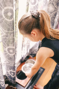 Chores for Kids by popular Nashville motherhood blog, Nashville Wifestyles: image of a young girl filling a dog water dish.