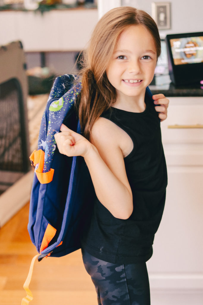 Back to School Tips by popular Nashville lifestyle blog, Nashville Wifestyles: image of a girl wearing a Dollar General backpack. 