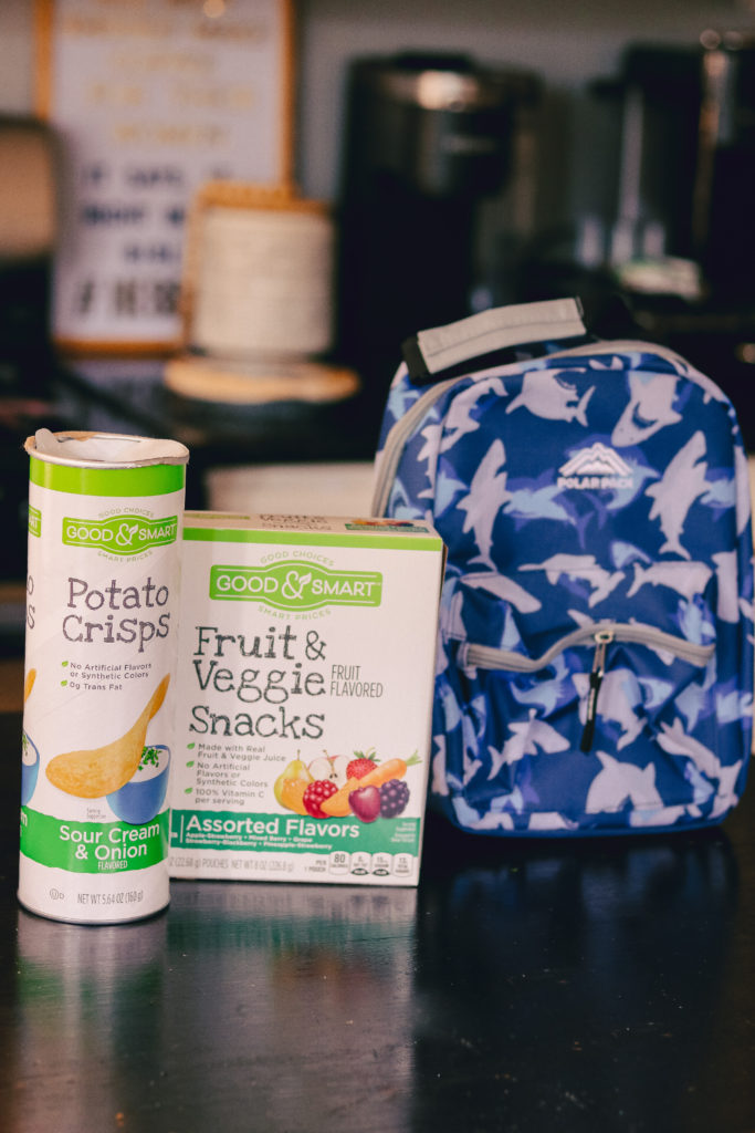 Back to School Tips by popular Nashville lifestyle blog, Nashville Wifestyles: image of Dollar General potato crisps and Dollar General fruit and vegetable snacks next to a Dollar General lunch box. 