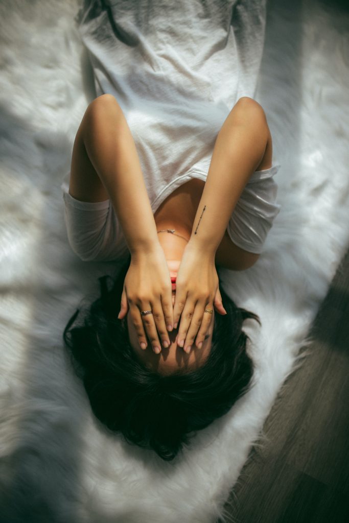 How to Cope With Grief by popular Nashville lifestyle blog, Nashville Wifestyles: image of a woman laying down and placing her hands over her face. 