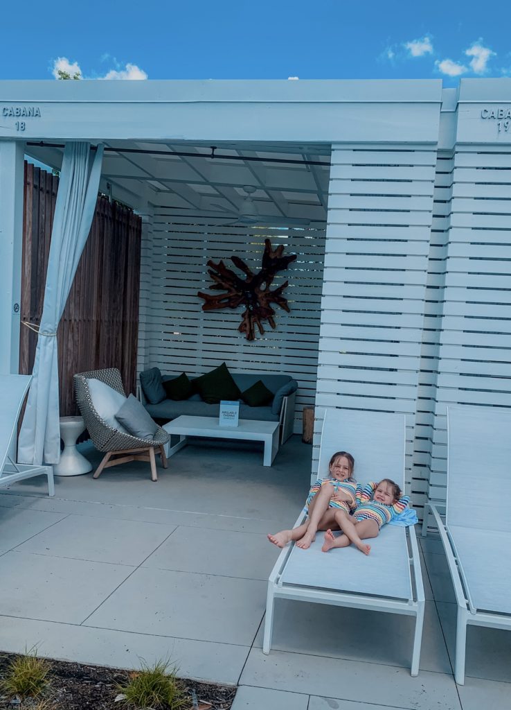 Soundwaves Water Park by popular Nashville blog, Nashville Wifestyles: image of two little girls wearing rainbow stripe rash guards and sitting on a white lounge chair.