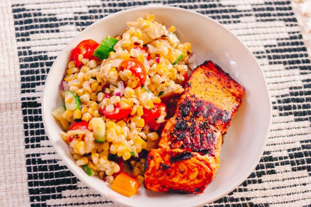 Summer Corn Salad Recipe by popular Nashville lifestyle blog, Nashville Wifestyles: image of summer corn salad and grilled salmon on a white ceramic plate. 