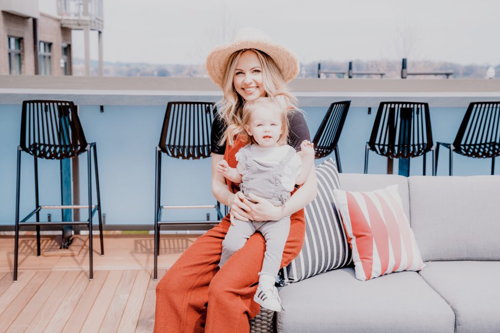 Acts of Kindness by popular Nashville motherhood blog, Nashville Wifestyles: image of a woman holding her toddler aged daughter and sitting on a grey couch on an outside patio deck. 