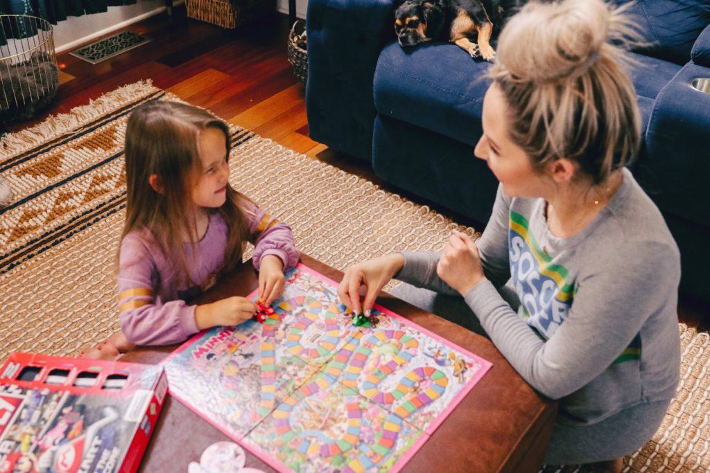 Family Board Games by popular Nashville motherhood blog, Nashville Wifestyles: image of a woman playing Candyland with her daughter. 