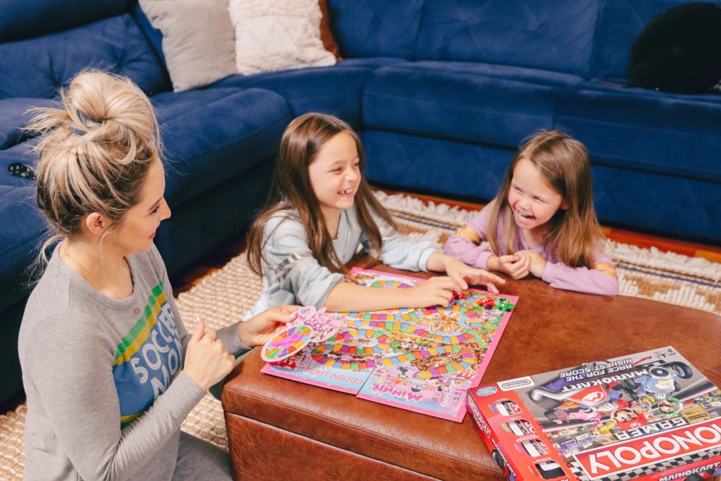 Family Board Games by popular Nashville motherhood blog, Nashville Wifestyles: image of a woman playing Candyland with her daughters.