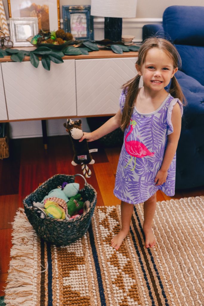 Chores for Kids by popular Nashville motherhood blog, Nashville Wifestyles: image of a young girl putting toys in a basket. 