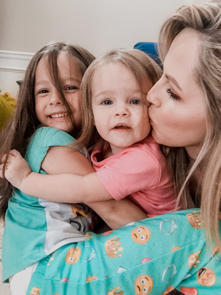 Acts of Kindness by popular Nashville motherhood blog, Nashville Wifestyles: image of a woman hugging and kissing her two young daughters. 