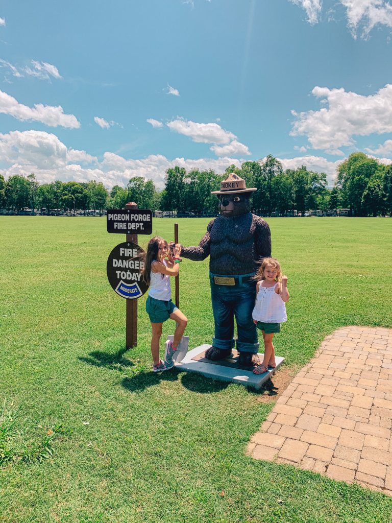 Pigeon Forge TN by popular Nashville travel blog, Nashville Wifestyles: image of two young girls standing next to a Smokey the Bear statue.