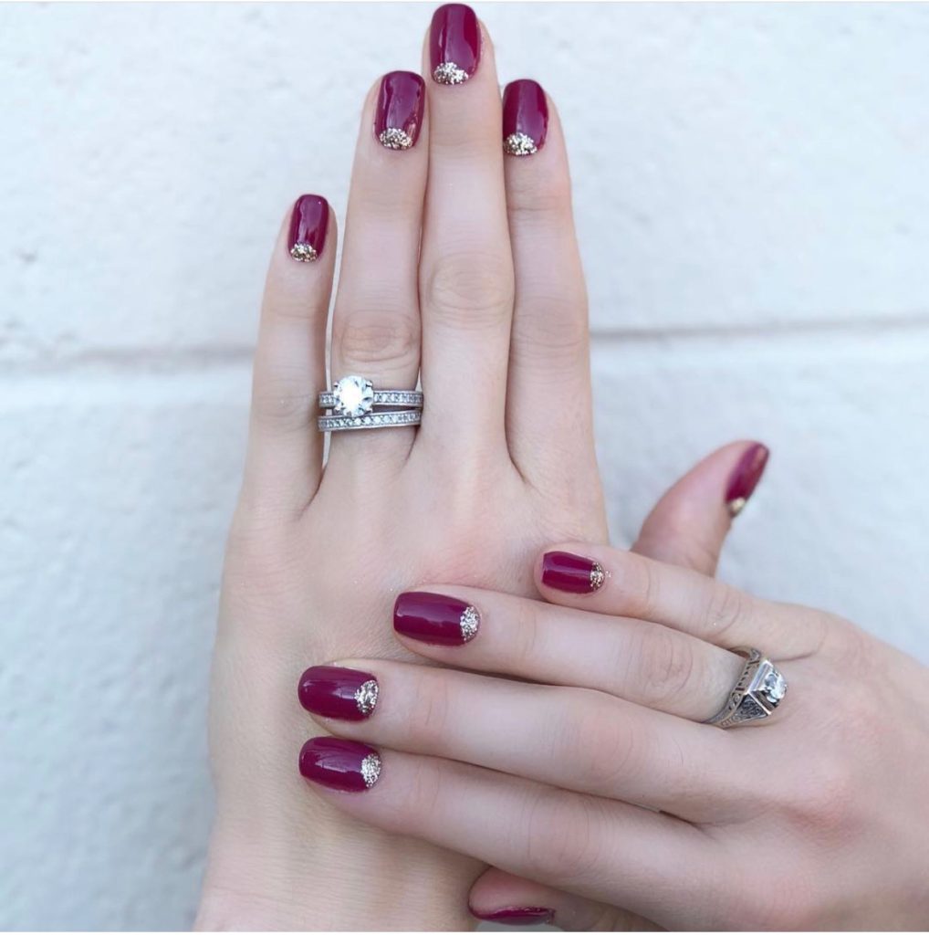 Nail Trends by popular Nashville beauty blog, Nashville Wifestyles: image of a woman with a berry color and gold glitter manicure. 