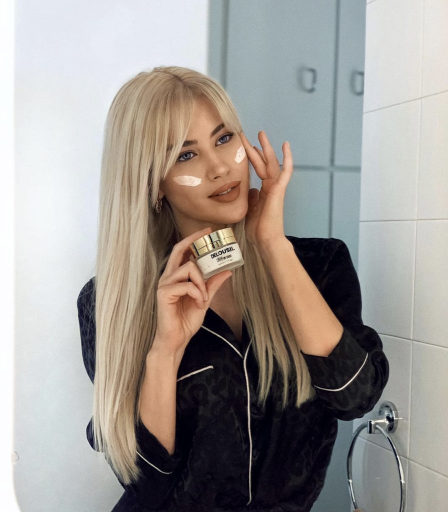 Curtain Bangs by popular Nashville beauty blog, Nashville Wifestyles: image of a woman with blonde hair and curtain bangs applying some face cream to her face. 