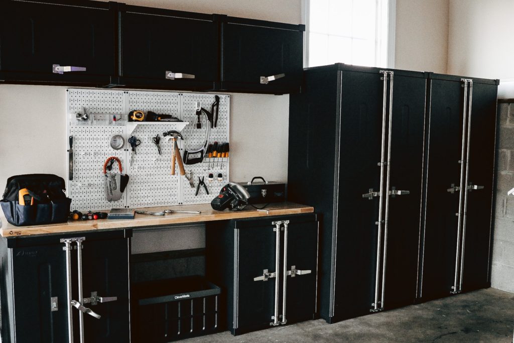 Garage Organization Ideas by popular Nashville life and style blog, Nashville Wifestyles: image of an organized garage with black cabinets and a work table. 