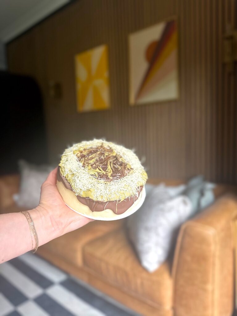 Store-bought cheesecake topped with melted chocolate, pistachio paste, and kataifi in a Dubai chocolate–inspired style.