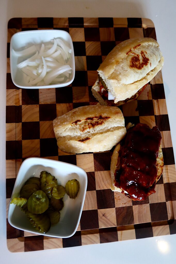 Homemade K-Rib sandwich with BBQ sauce, pickles, and onions