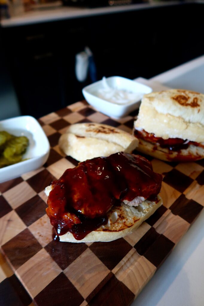 Homemade K-Rib sandwich with BBQ sauce, pickles, and onions